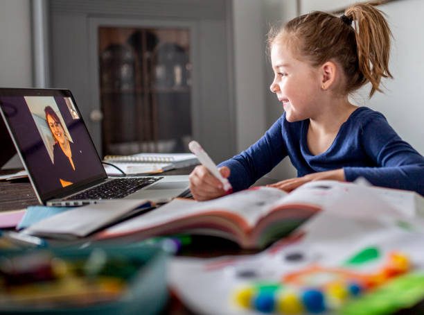 Little girl doing homework with a teacher on a laptop.